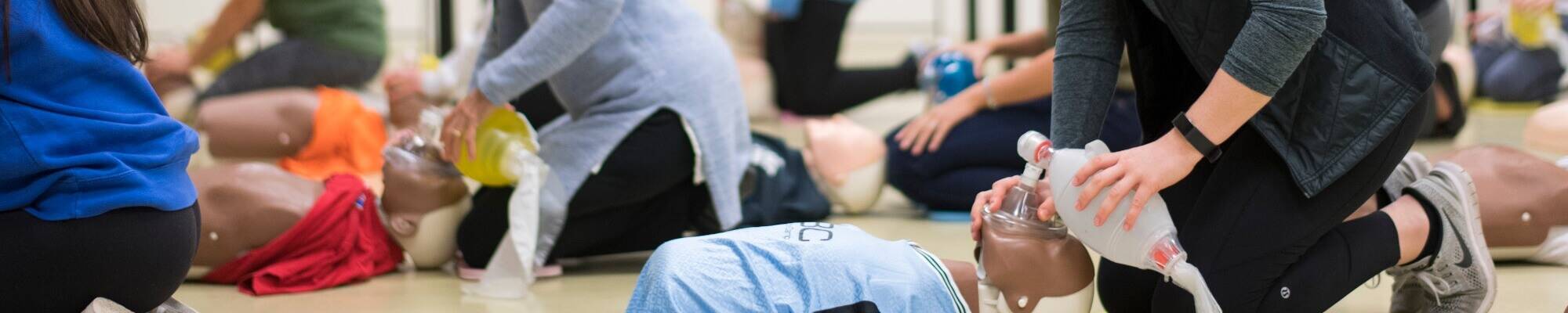 A group of people kneeling next to CPR mannikins.
